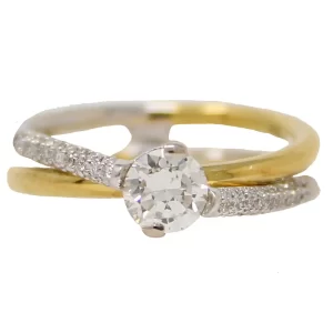 round center stone where a yellow gold band and white gold band cross; white gold band is accented with round diamonds on both sides of the center stone