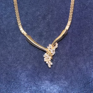 stylized V adorned with 26 small round diamonds in a floral pattern attached to a heavy flat chain