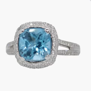cushion cut swiss blue topaz surround by a halo of round diamonds with round diamonds accenting the shank